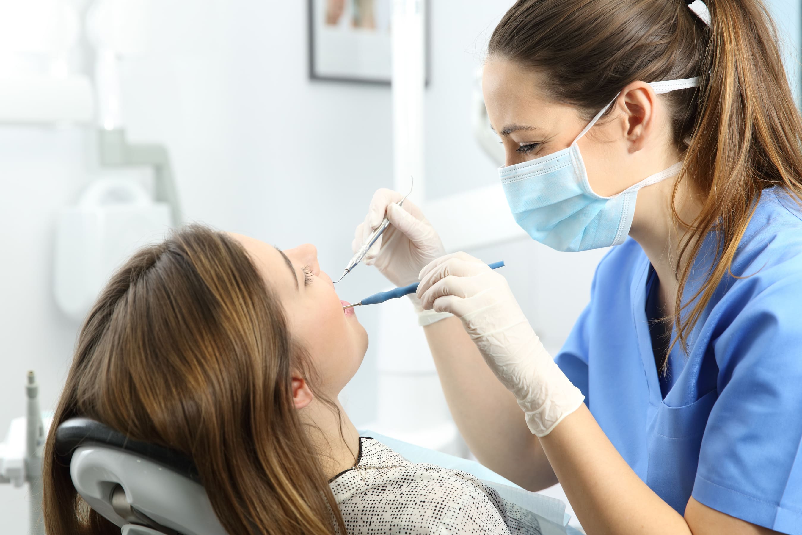 dentista haciéndole una limpieza bucal a una clienta
